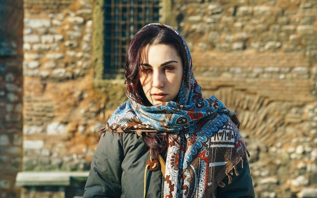 Photo portrait of young woman wearing scarf while standing outdoors during sunny day