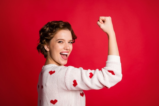 Portrait of a young woman wearing stylish trendy jumper isolated on red wall