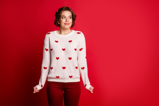 Photo portrait of a young woman wearing stylish trendy jumper isolated on red wall