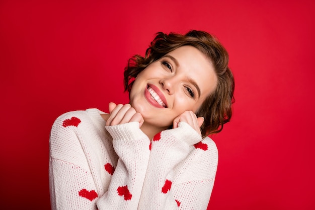 Portrait of a young woman wearing stylish trendy jumper isolated on red wall