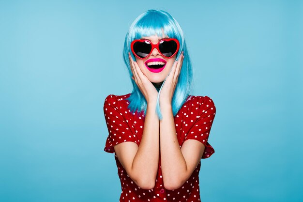 Portrait of young woman wearing sunglasses against blue background