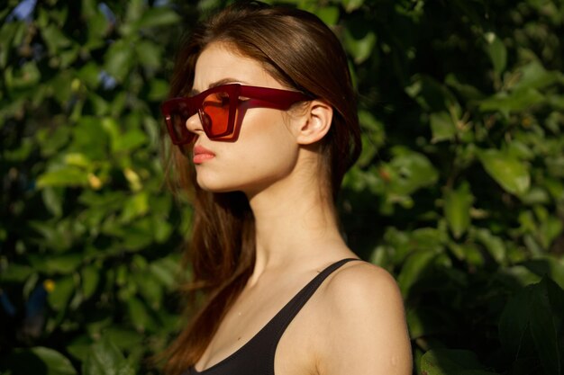 Portrait of young woman wearing sunglasses against plants