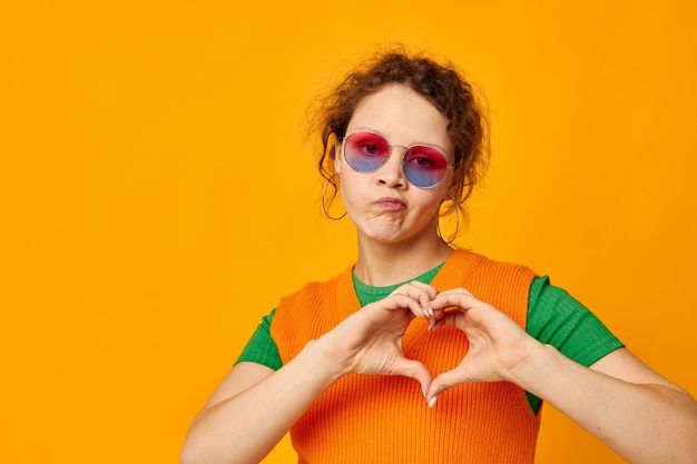 Photo portrait of young woman wearing sunglasses against yellow background