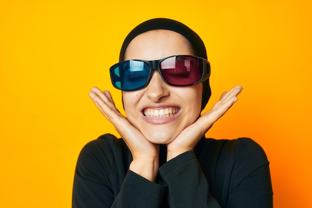 Portrait of young woman wearing sunglasses against yellow background