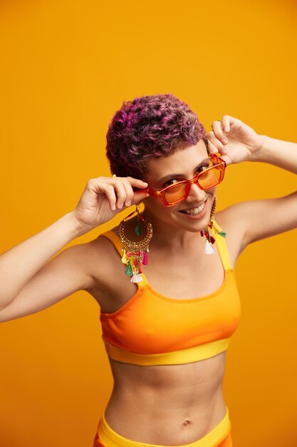 Portrait of young woman wearing sunglasses against yellow background