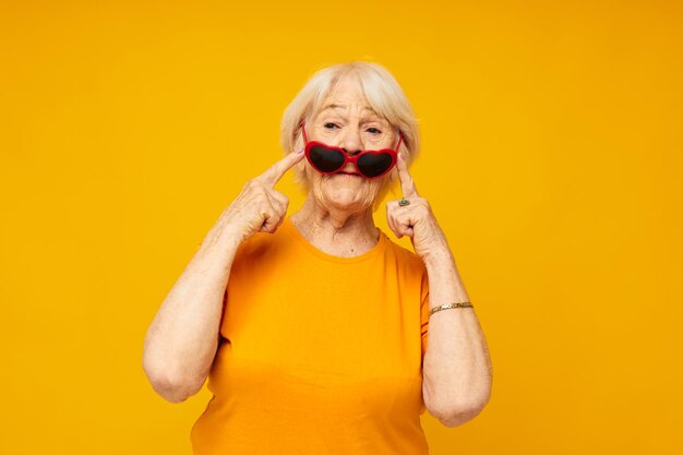 Portrait of young woman wearing sunglasses against yellow background