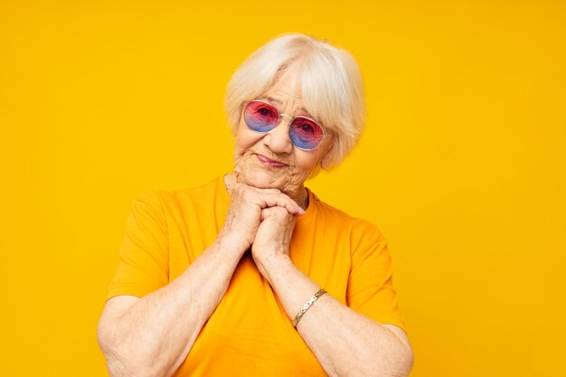 Portrait of young woman wearing sunglasses against yellow background