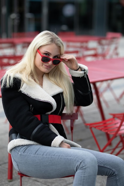 portrait of young woman wearing sunglasses sitting on chair