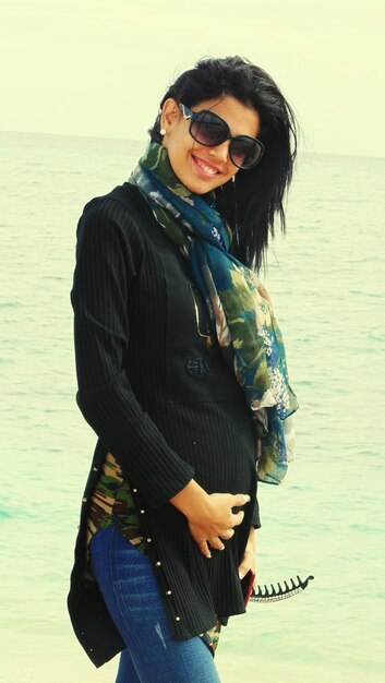 Photo portrait of young woman wearing sunglasses standing at beach