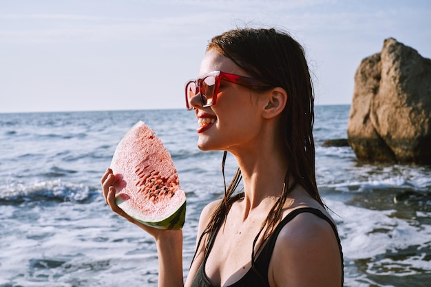 Portrait of young woman wearing sunglasses while standing at beach