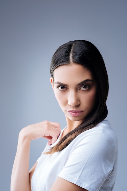 portrait of a young woman in white t-shirt posing against a gray wall