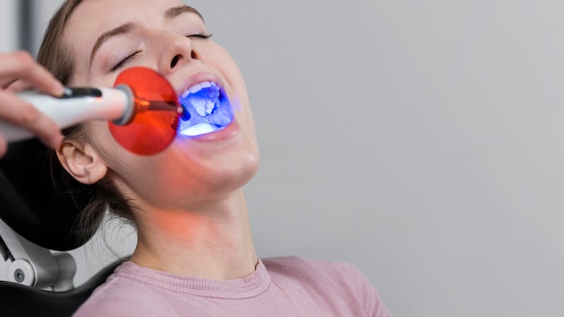 Portrait of young woman whitening her teeth