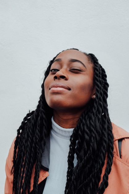 Portrait of young woman winking against wall