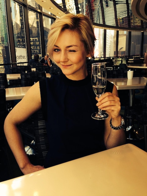 Photo portrait of young woman winking while holding champagne glass