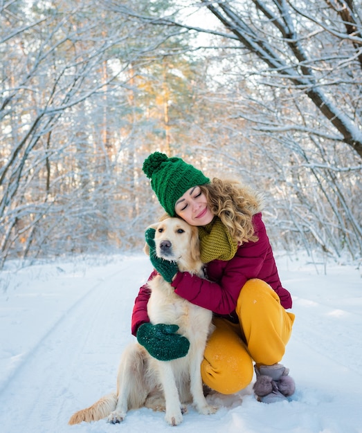 Portrait of young woman in winter park playing with her dog