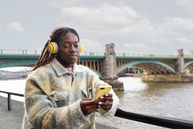 Foto ritratto di giovane donna con dreadlocks afro e cuffie in città