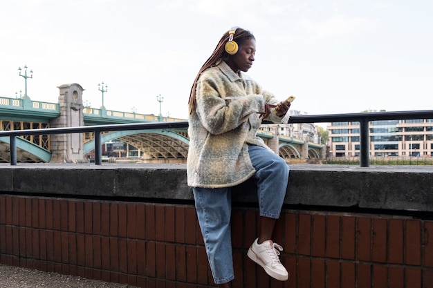 Photo portrait of young woman with afro dreadlocks and headphones in the city