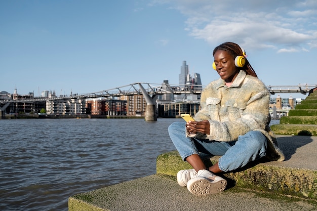 Портрет молодой женщины с афро дредами и наушниками в городе