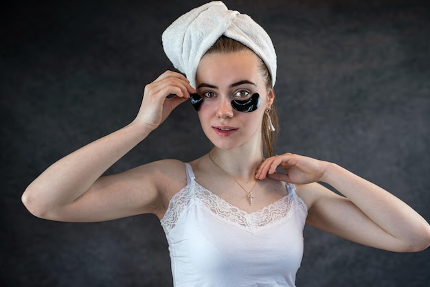 Portrait of young woman with applied black beauty patches isolated on black background