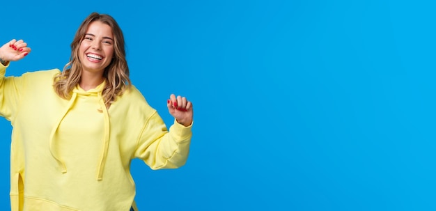 Portrait of young woman with arms raised against blue background