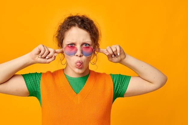 Photo portrait of young woman with arms raised against yellow background