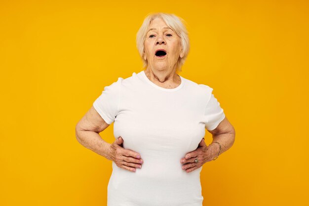 Portrait of young woman with arms raised against yellow background