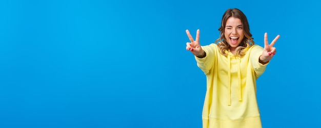 Foto ritratto di una giovane donna con le braccia alzate in piedi sullo sfondo blu