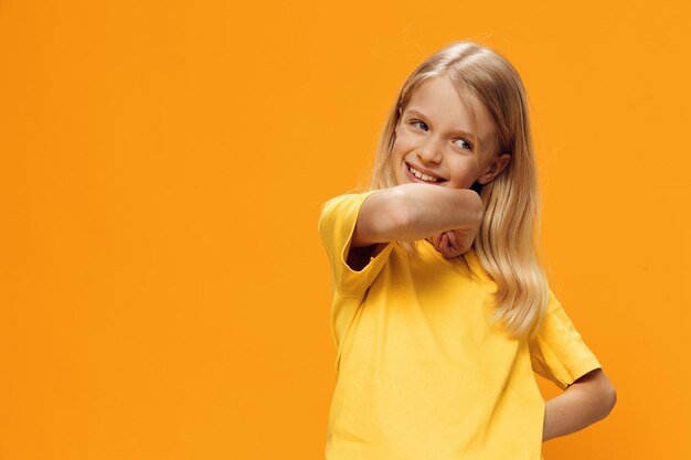 Photo portrait of young woman with arms raised standing against yellow background