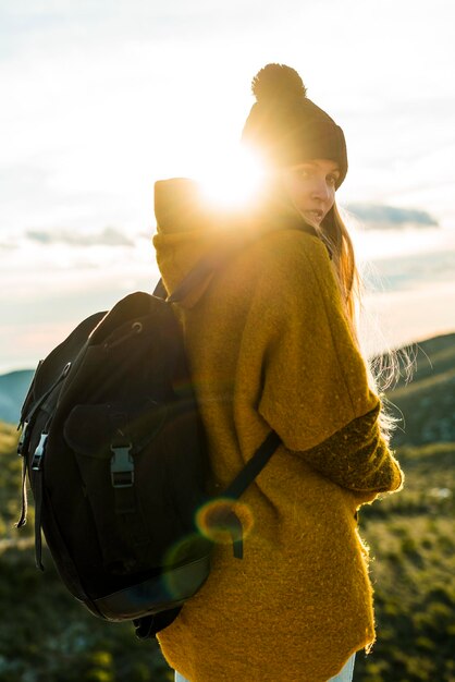 Photo portrait of young woman with backpack in nature at sunset