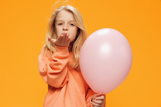 Portrait of young woman with balloons against yellow background