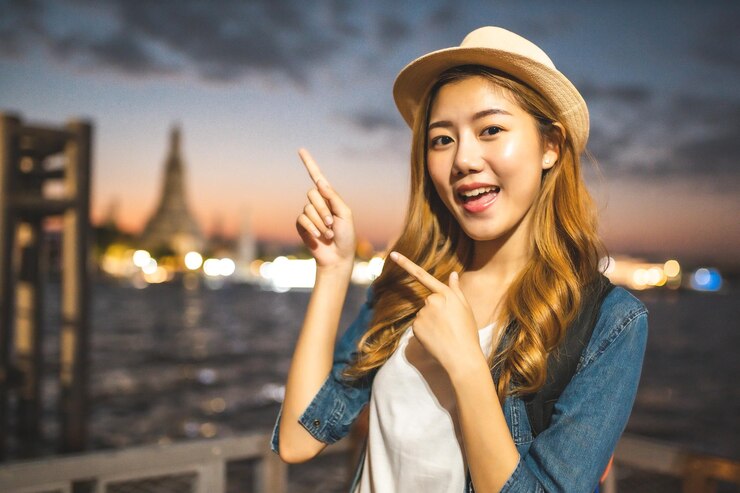 Photo 夕暮れの空を指している金の若い女性の肖像画