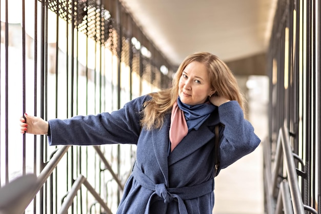 Foto ritratto di una giovane donna con i capelli biondi in un cappotto blu a molla