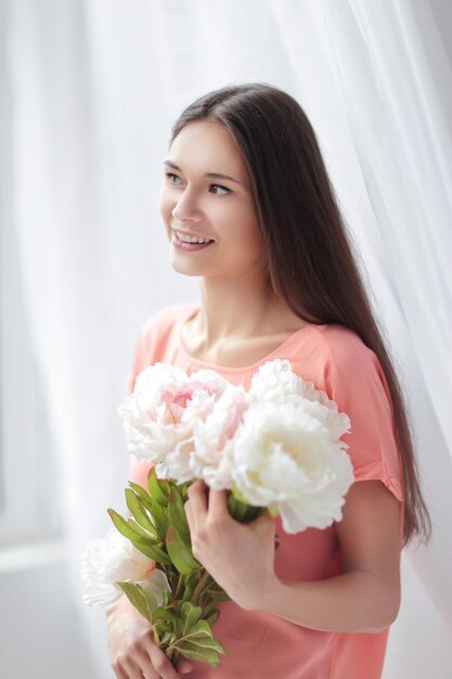 Portrait of a young woman with a bouquet of peonies