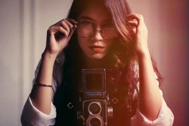 Portrait of young woman with camera sitting at home