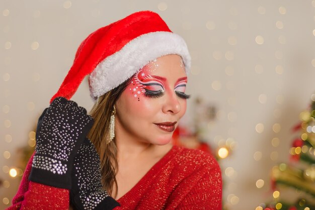 Foto ritratto di giovane donna con trucco natalizio e cappello da babbo natale sfondo natalizio