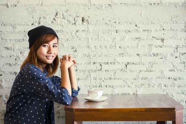 カフェに座っているテーブルにコーヒーカップを持った若い女性の肖像画