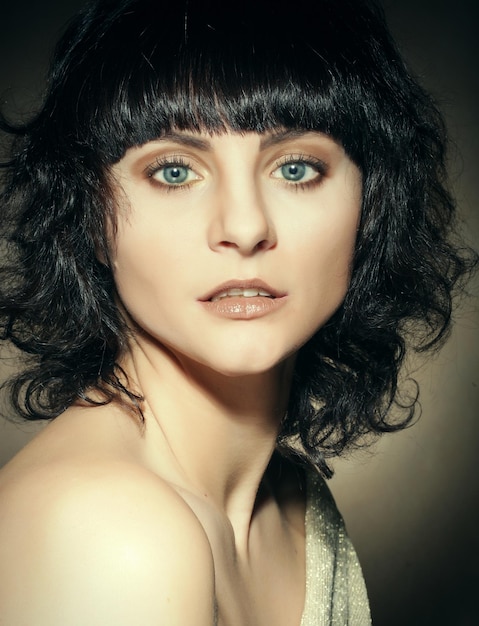 Portrait of a young woman with curly hair over dark background