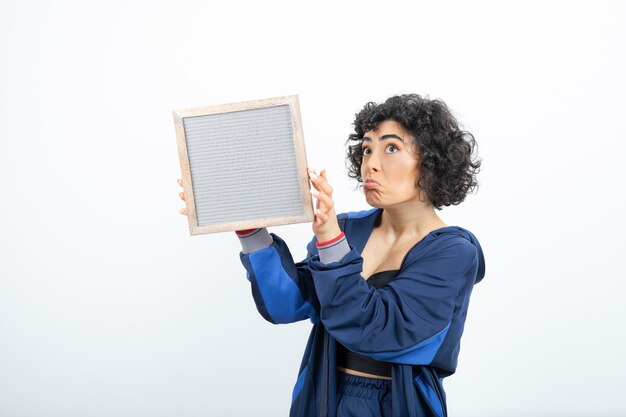 Portrait of a young woman with curly hair holding frame .