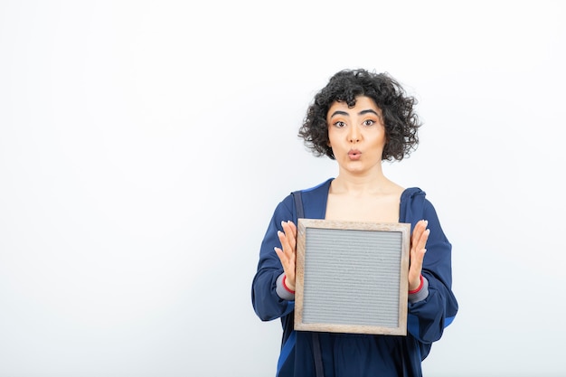 Portrait of a young woman with curly hair holding frame .