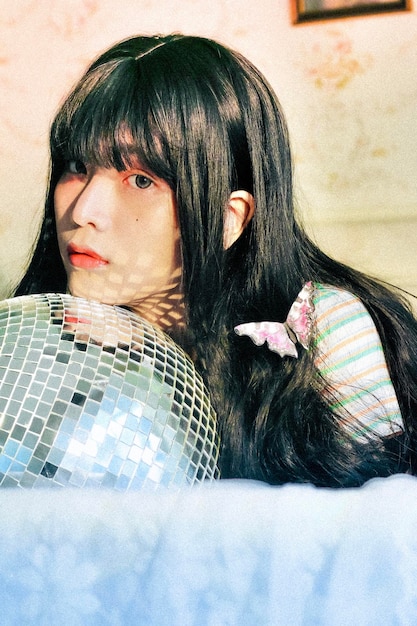 Photo portrait of young woman with disco ball lying on bed