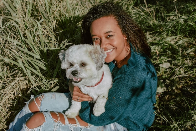 Photo portrait of young woman with dog sitting on grass