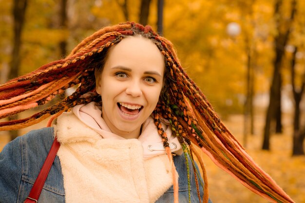 Portrait of a young woman with dreadlocks in the autumn park