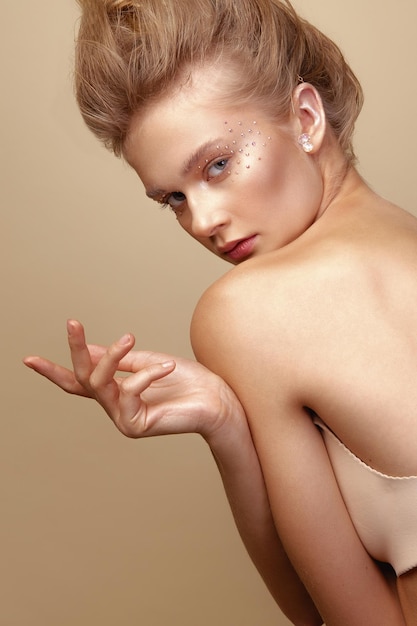 Photo portrait of young woman with eye make-up against brown background