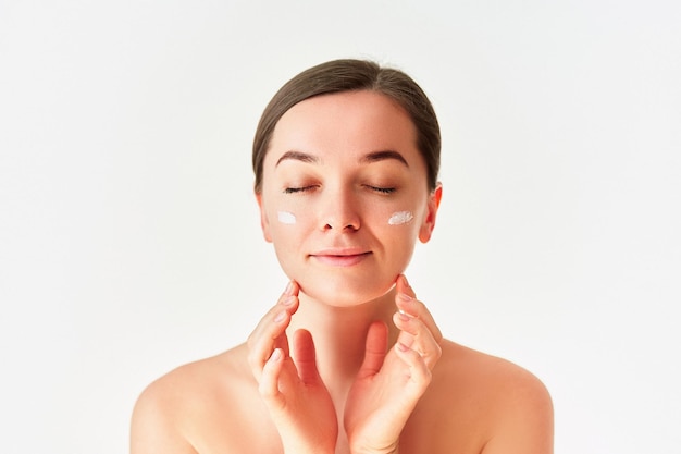 Portrait of young woman with facial cream for beautiful healthy skin on white background