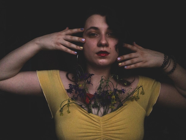 Photo portrait of young woman with flowers against black background