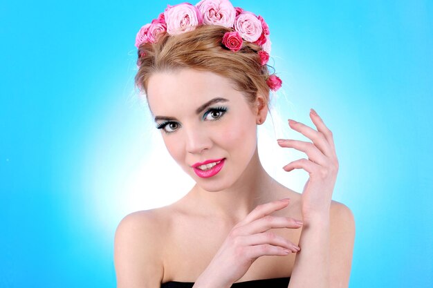 Photo portrait of young woman with flowers in hair on blue background