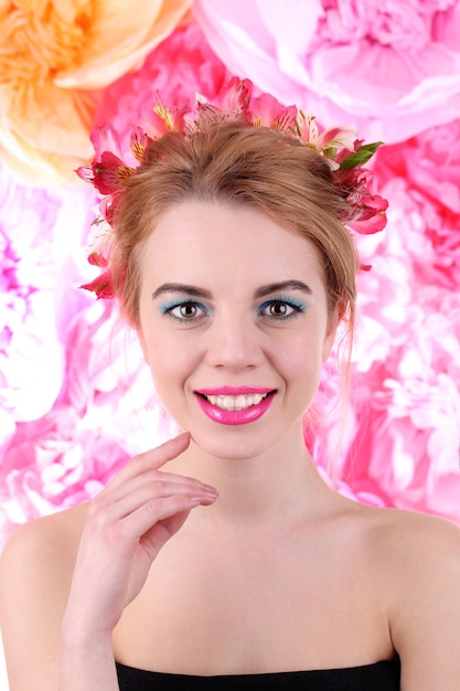 밝은 분홍색 배경에 머리에 꽃을 꽂은 젊은 여성의 초상화