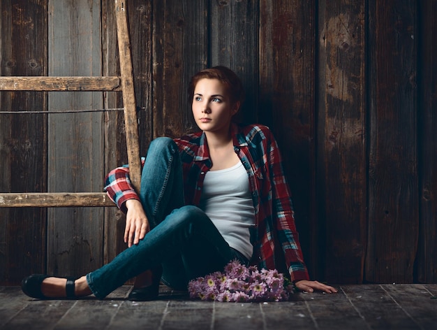 Portrait of a young woman with flowers on wooden background