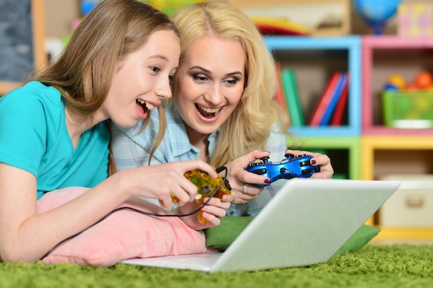 Portrait of young woman with girl using laptop at home