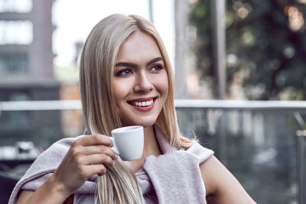 Ritratto di giovane donna con gli occhiali che beve caffè al bar relax